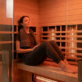 Femme détendue avec une serviette dans un sauna infrarouge moderne en bois.