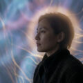 Profil d'une femme devant une projection abstraite rappelant des connexions neuronales ou une nébuleuse lumineuse.
